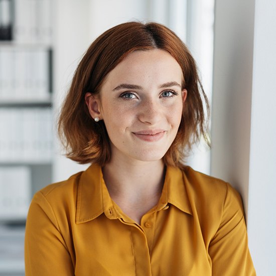 Woman in orange shirt smiling in office