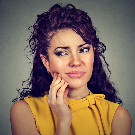 woman holding cheek in pain