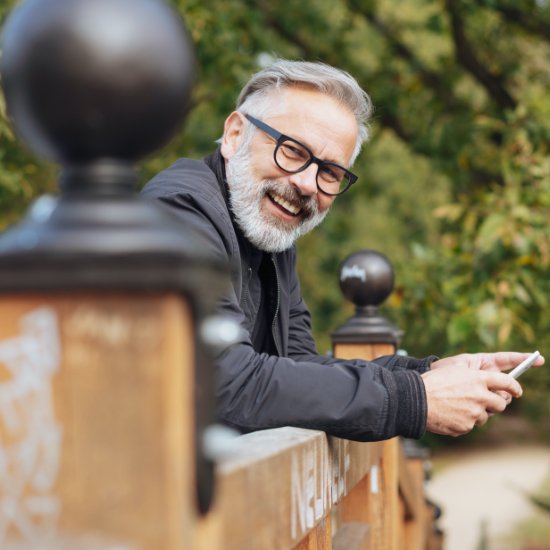 man with glasses smiling on bridge