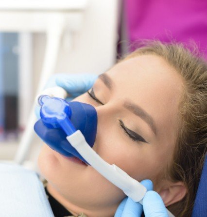 Young woman with a nitrous oxide sedation mask in dental chair