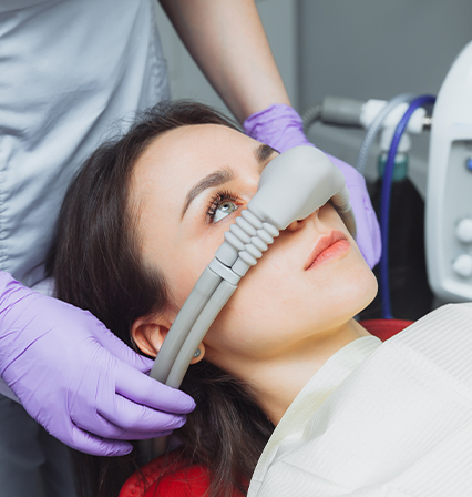 Young woman with a nitrous oxide sedation mask in dental chair