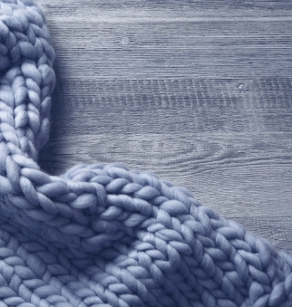 Gray knitted blanket lying on wooden surface