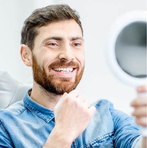 Dental patient looking at his smile in mirror