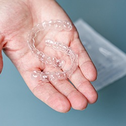 person holding two clear aligners 