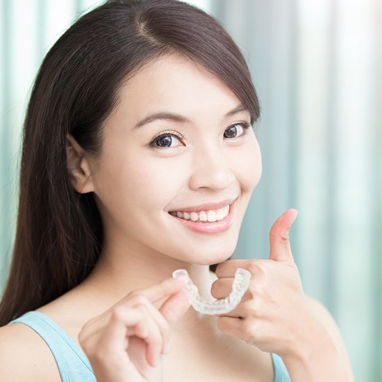 woman holding invisalign and doing thumbs up