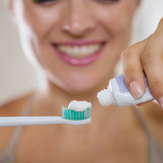 woman holding toothpaste and brush