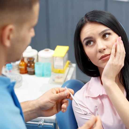 Patient in Grand Island holding cheek due to dental implant failure