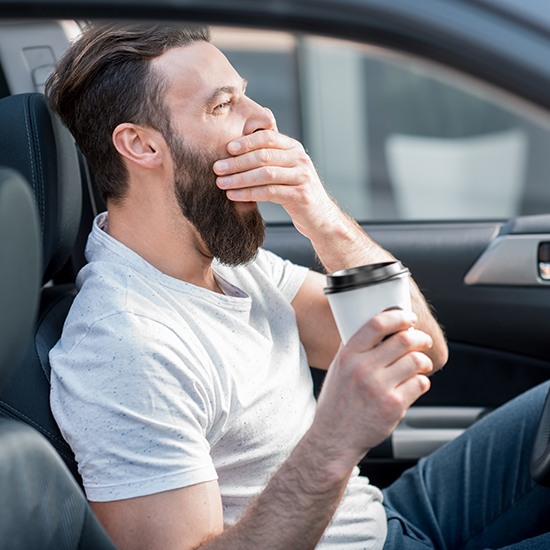 man holding coffee and yawning