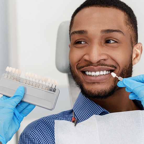 man smiling by veneer shade chart