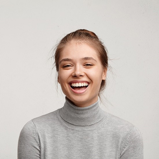 young woman smiling after getting veneers in Grand Island